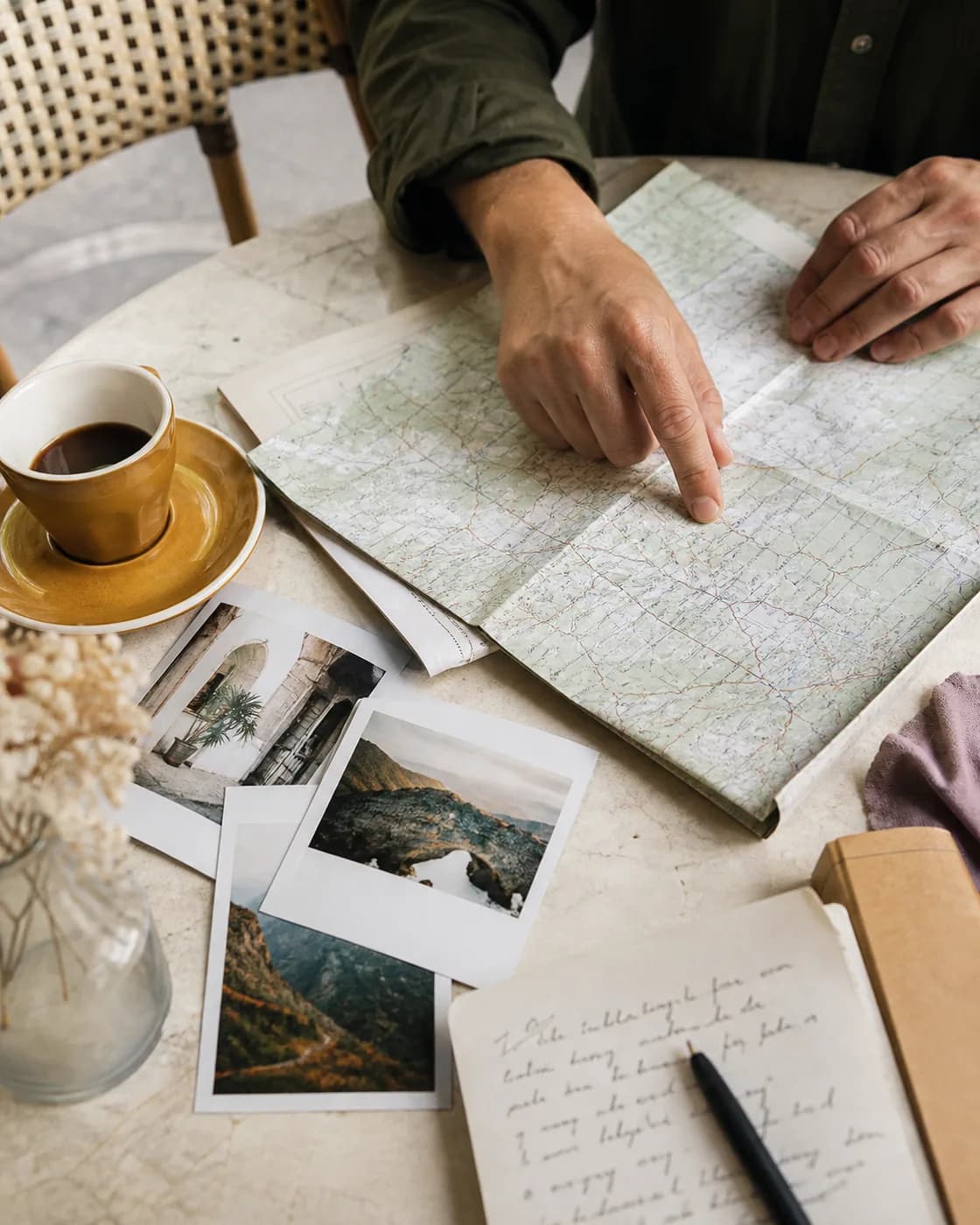 Travel notes, a paper map, and photographs arranged on a table for planning a trip.
